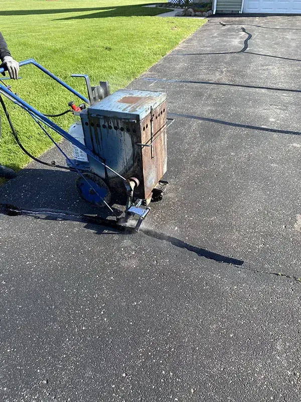 A hot-pour crack filling machine working along a crack in an asphalt driveway