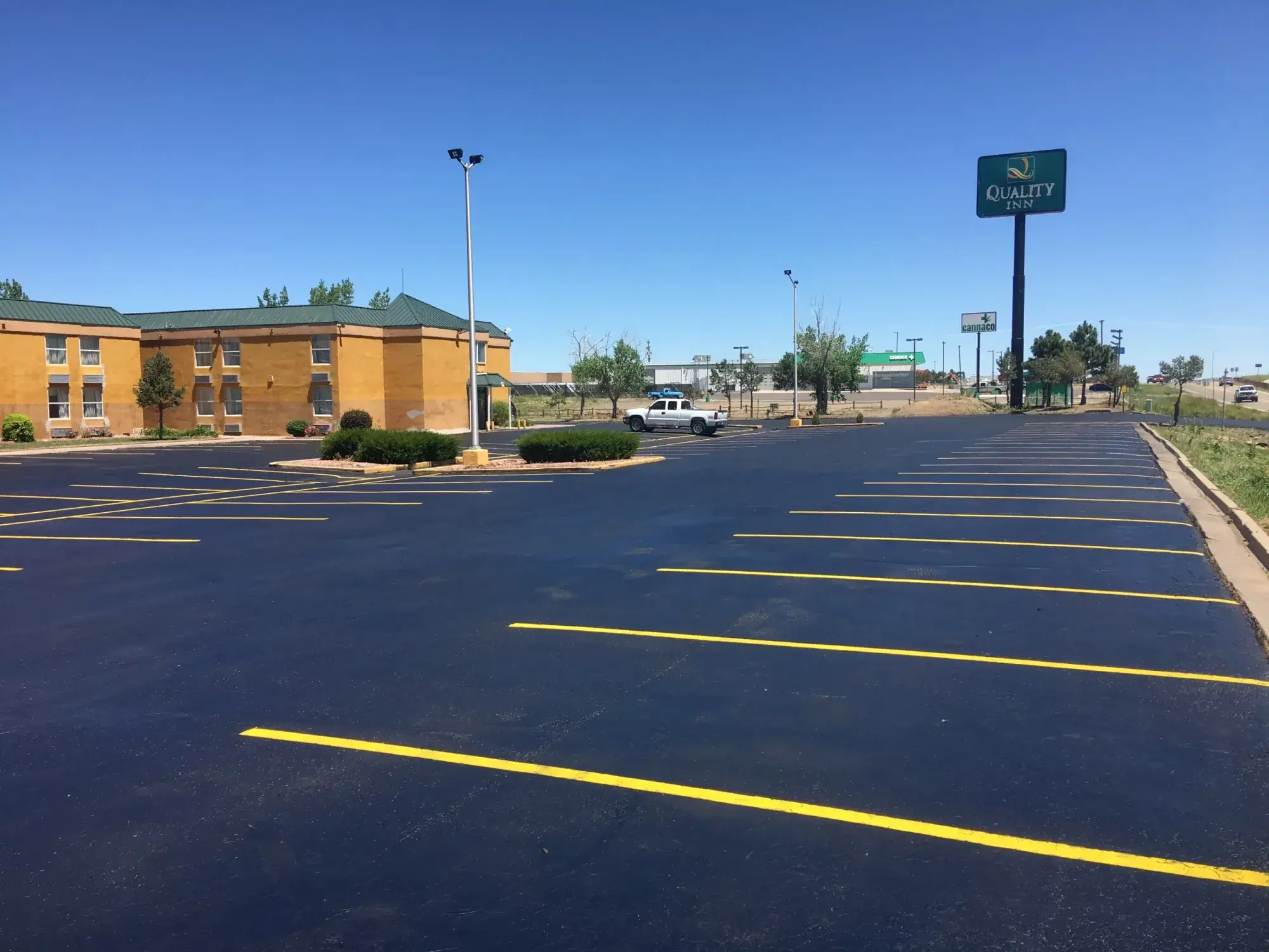 A freshly sealed and striped commercial parking lot with bright yellow stall lines