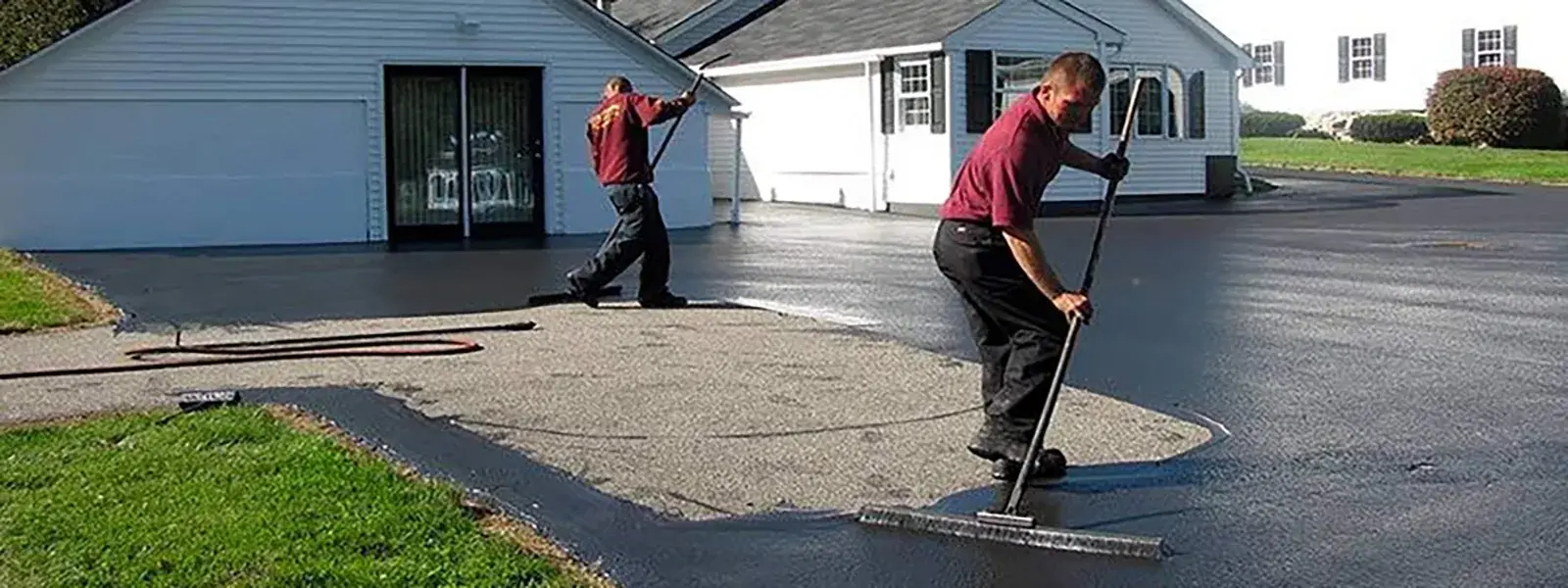 Two workers sealcoating a commercial parking lot with squeegees